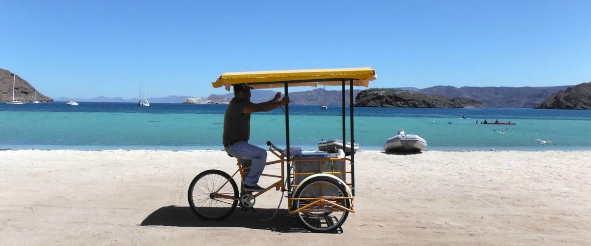 A vendor pedals by on this gorgeous beach